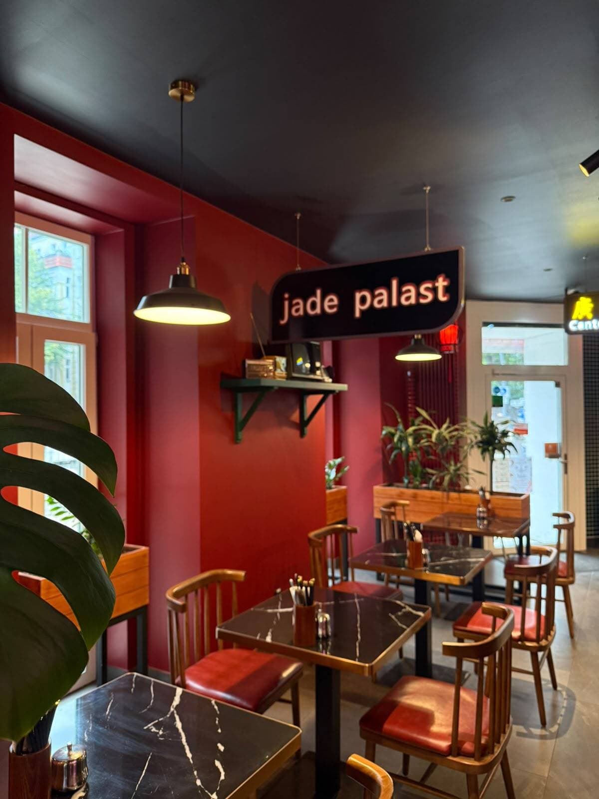Gemütlicher Gastraum im Jade Palast mit rot gestrichenen Wänden und Marmortischen